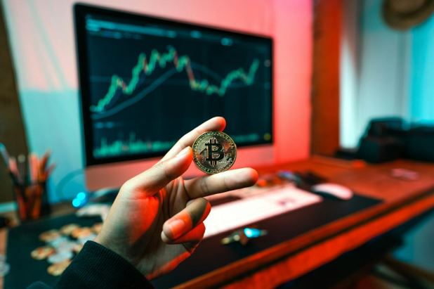 A person holding and showing a golden Bitcoin